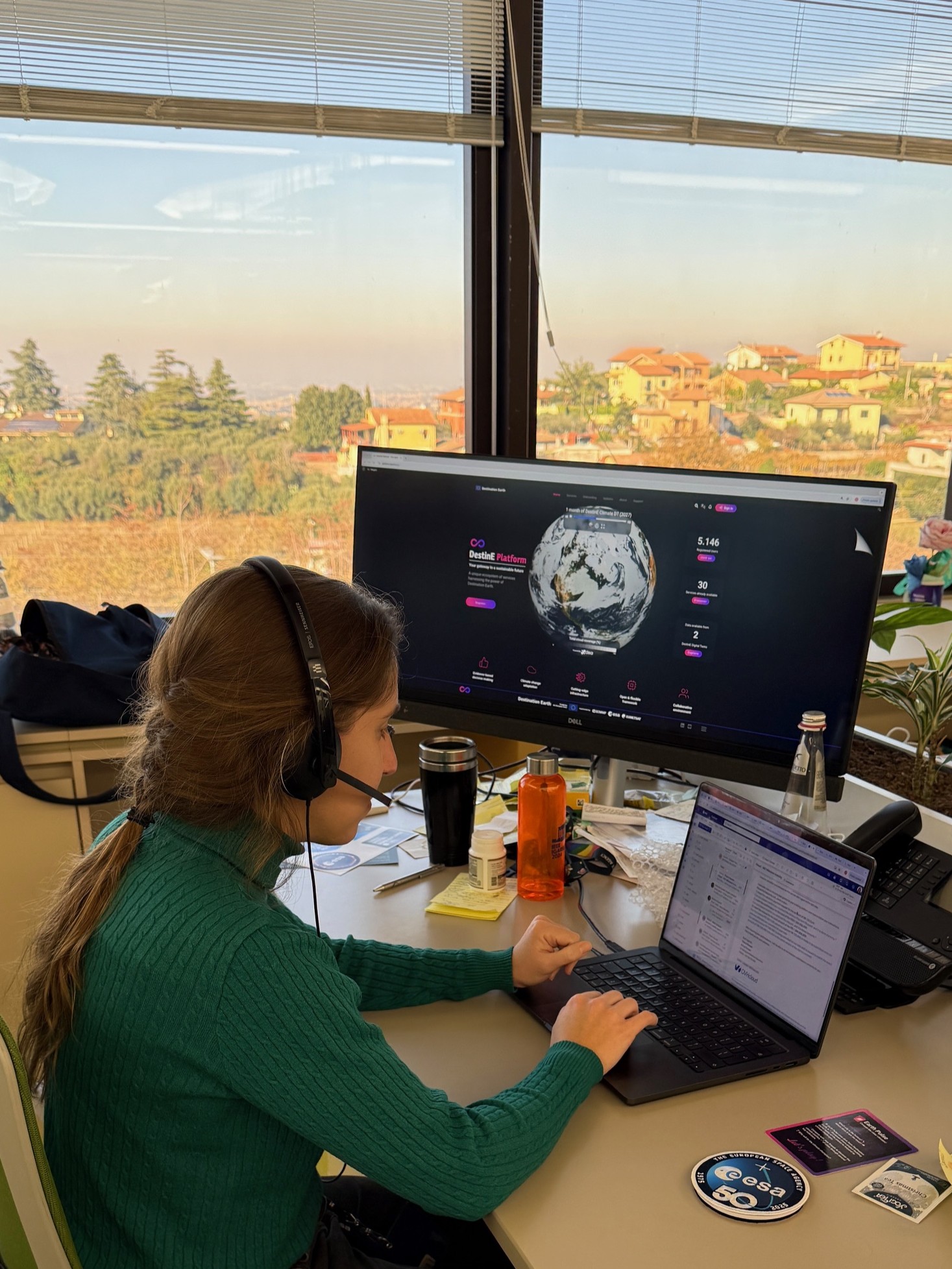 A woman is sitting at a desk working on her laptop.